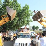 JCB Machine से पुष्प वर्षा कर किया स्वागत