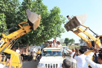 JCB Machine से पुष्प वर्षा कर किया स्वागत