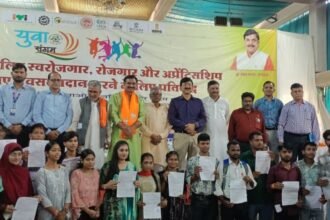 गुना में आयोजित रोजगार और स्वरोजगार कार्यक्रम में हितग्राहियों को लाभ वितरित करते अधिकारी